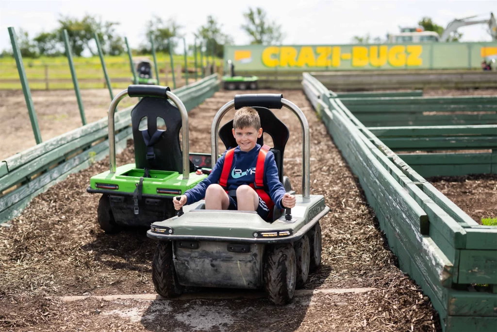 Young boy enjoying a ride in a small motorized vehicle on a fun outdoor track.