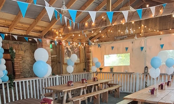 Cosy wooden seating area with blue and white bunting and balloons, perfect for gatherings and celebrations.