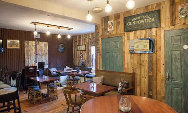 Cosy Irish pub interior with wooden tables, vintage signs, and warm lighting.
